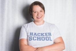 Julia Freudenberg ist Geschäftsführerin der Hacker School – sie steht ihn einem T-Shirt der Firma vor einem weißen Hintergrund.