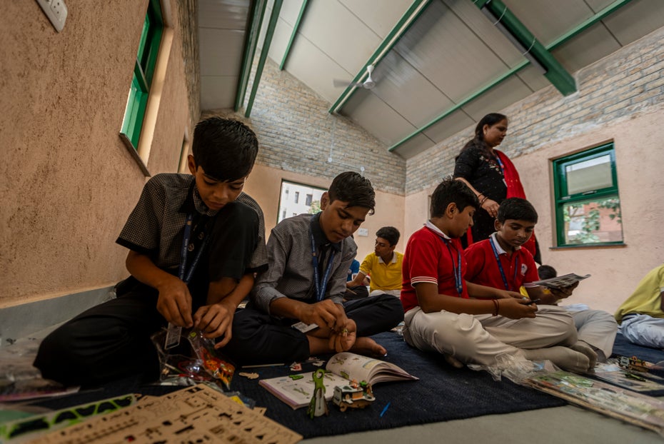 Indische Kinder lernen in einer Schule, die aus Zuckerrohrabfällen gebaut wurde.