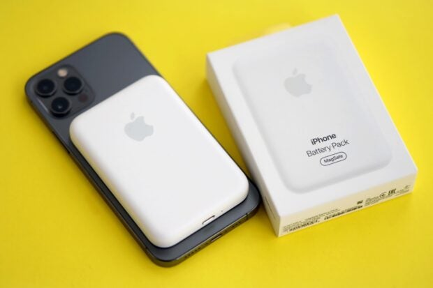 Ein iPhone mit externem Akku liegt neben einer Produktverpackung.