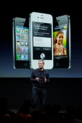 Tim Cook präsentiert das iPhone 4s, das im Hintergrund zu sehen ist.