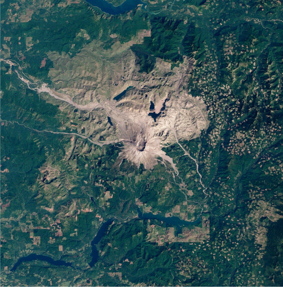 Die Satelliten-Aufnahme zeigt größtenteils grüne Landschaft, mittig ist die grau-braune Vulkanlandschaft zu sehen, unten und oben im Bild sind blaue Stauseen zu sehen..