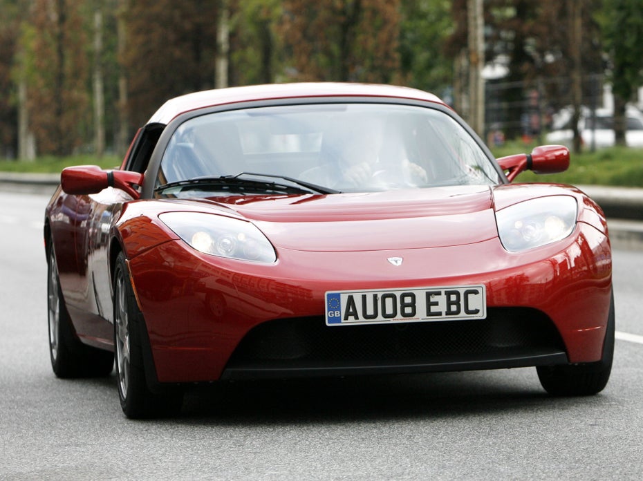 Ein roter Tesla Roadster fährt auf der Straße