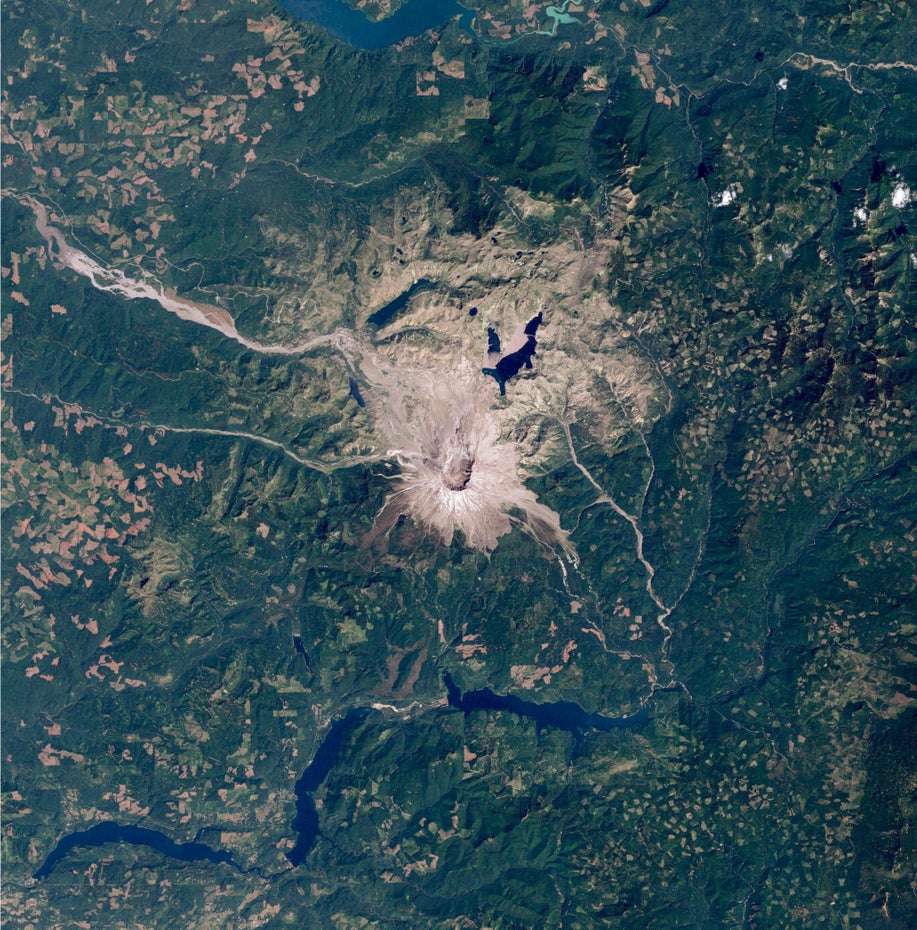 Schnee liegt um den Krater des Mount St. Helens, oben und unten im Bild sind blaue Stauseen zu sehen.