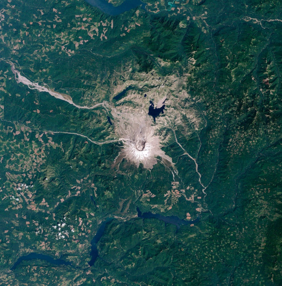 Der grau-braune Mount St. Helens liegt mit seiner gleichfarbigen Umgebung in grüner Landschaft.