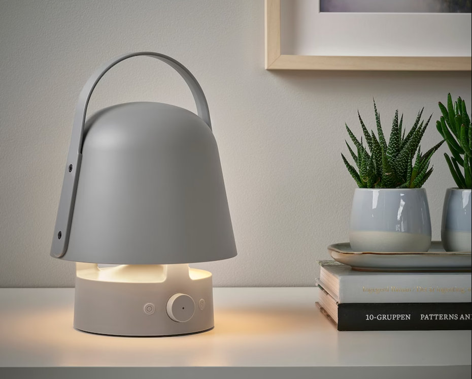 Eine kleine pilzförmige Lampe steht auf einem Tisch mit Büchern und kleinen Kakteen