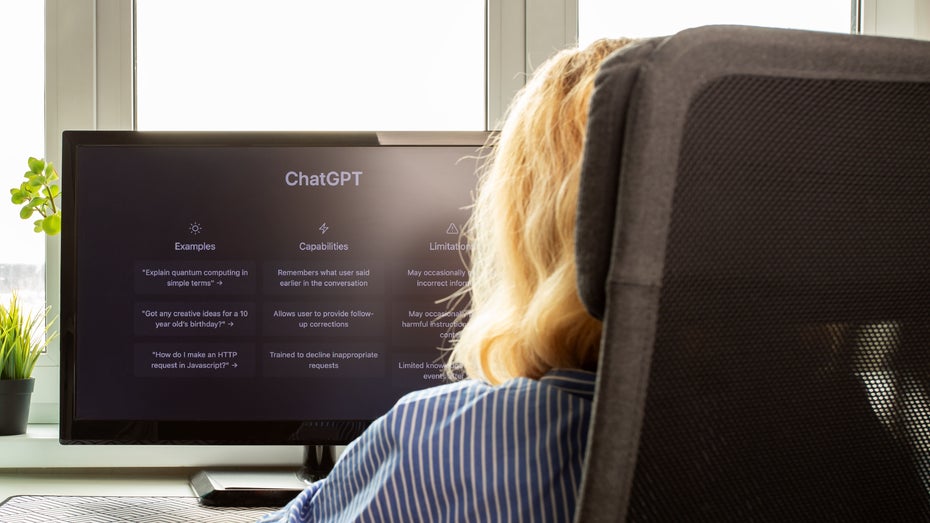 Eine Frau ist seitlich von hinten zu sehen, sie schaut auf einen Computerbildschirm, auf dem „ChatGPT” steht.