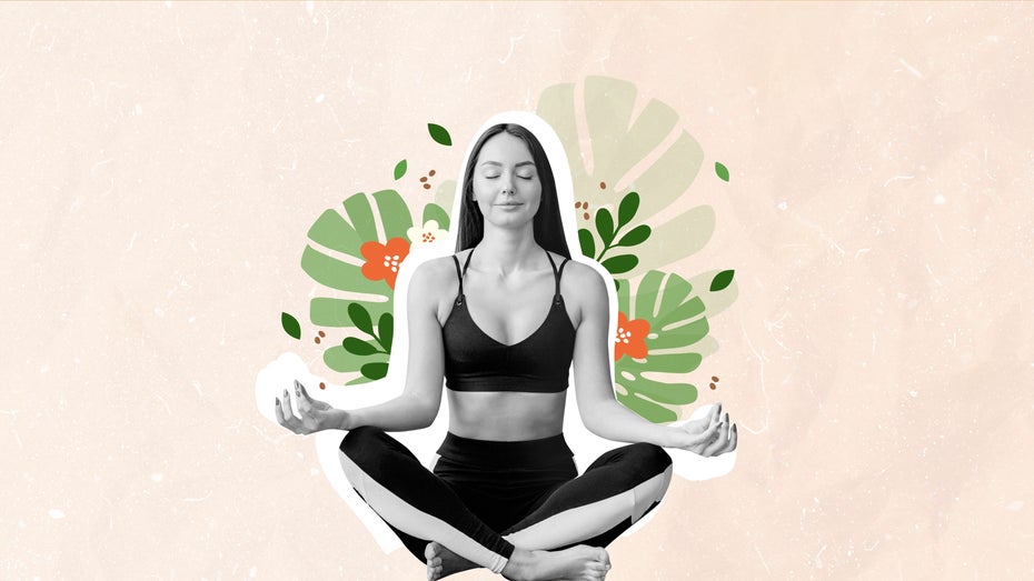 Eine Frau sitzt im Schneidersitz und Sportkleidung vor einem hellen Hintergrund.(Bild: E.Va / Shutterstock)