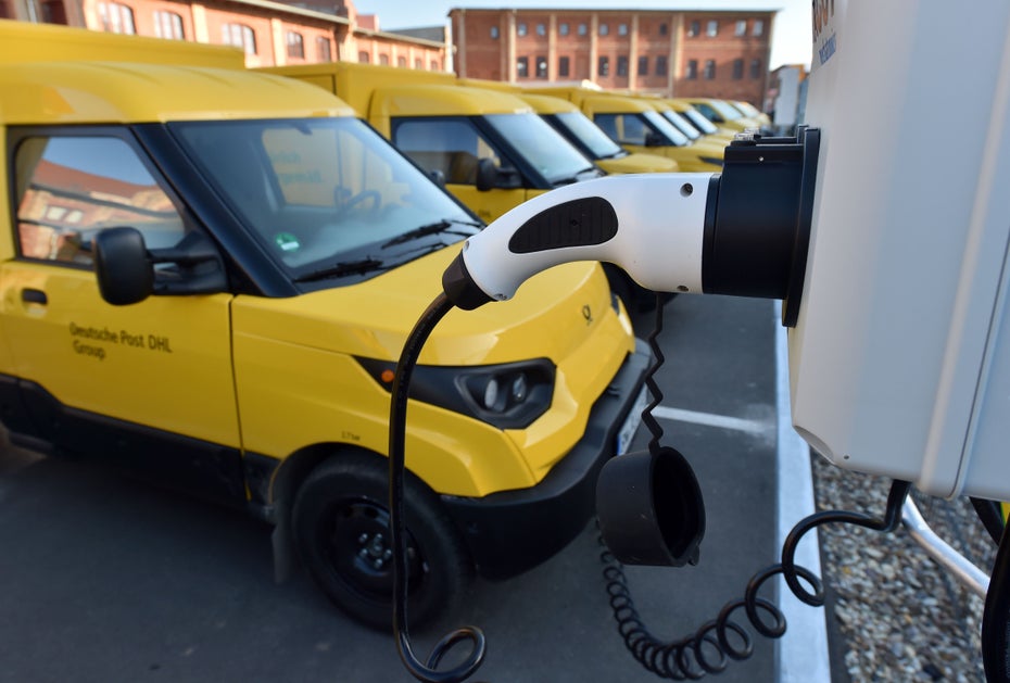 Eine Reihe gelber Postautos steht zum Aufladen auf Parkplätzen