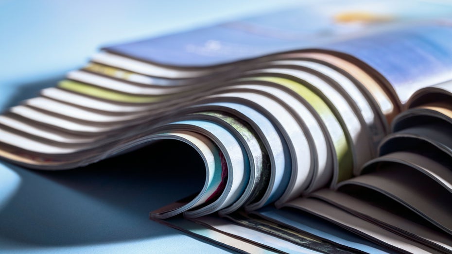 Mehrere Magazine liegen aufgeschlagen übereinander.