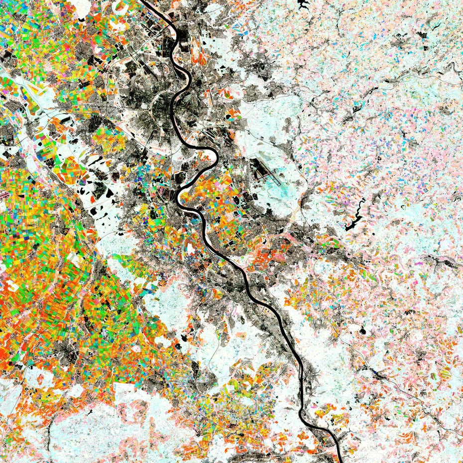 Das Bild zeigt den Rhein und die Städte Köln und Bonn von oben. Die Landschaft sieht aus wie ein bunter Flickenteppich, der Rhein zieht sich wie ein dunkles Band hindurch.