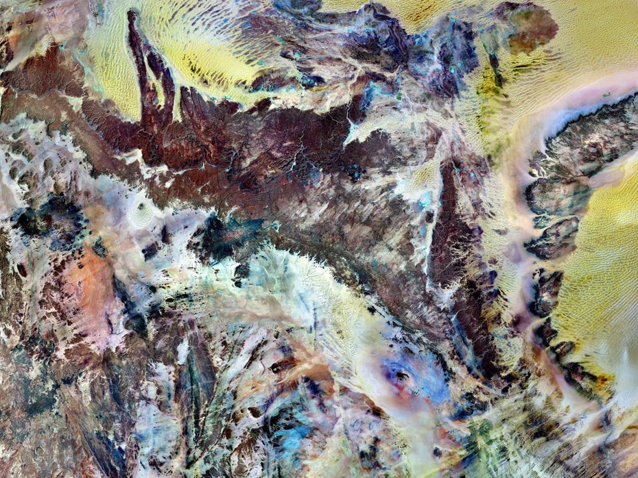 Eine in Gelb, Blau, Braun, Weiß und Grün gefärbte Felslandschaft.