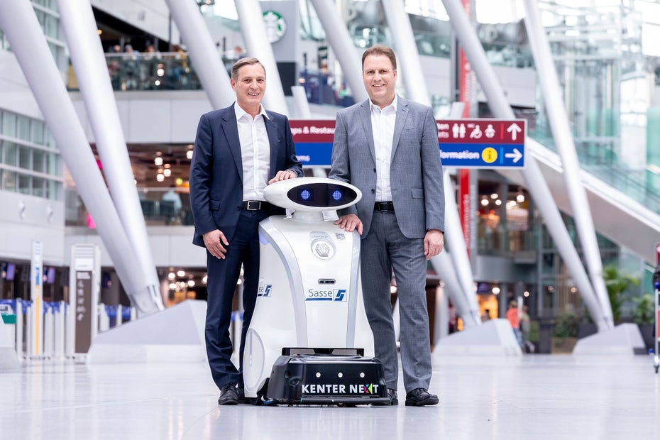 Thomas Jessberger, Geschäftsführer von Sasse Aviation Service und Stefan Beitelsmann, Leiter Infrastruktur beim Flughafen Düsseldorf posieren mit einem hüfthohen Roboter