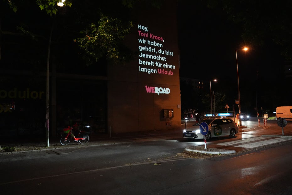Ein Plakat des Unternehmens WeRoad ist in Berlin bei Nacht zu sehen.