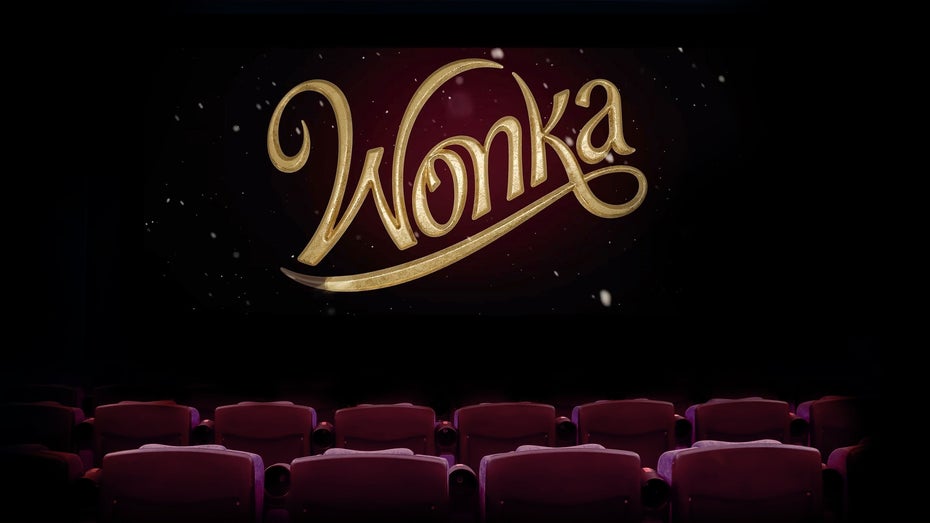 In goldener Schrift steht Wonka auf dunklem Hintergrund, davor sind Kinosessel zu sehen.